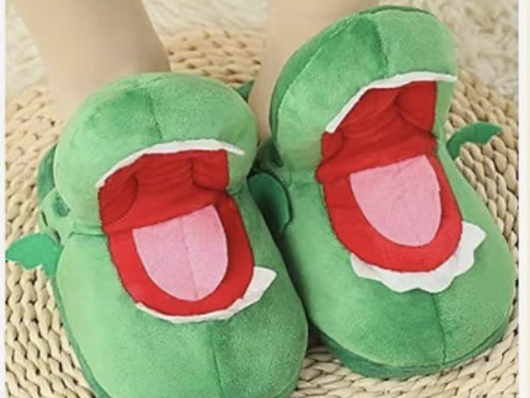 Deux chaussons crocodile en peluche, gueule grande ouverte et langue rose, posés sur un tapis tressé.