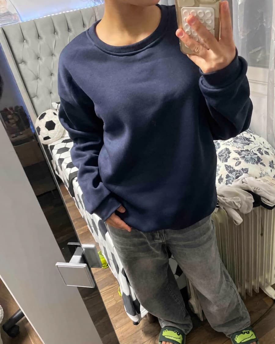 Les claquettes crocodile portées avec un jean gris, photographiées dans un miroir.