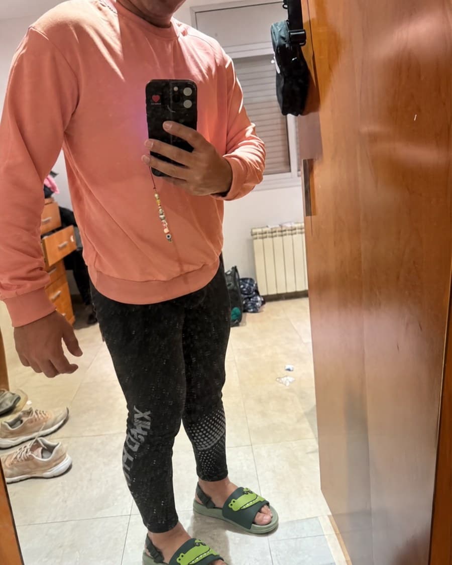 Les claquettes crocodile portées avec un sweat corail et un legging, photographiées dans un miroir.